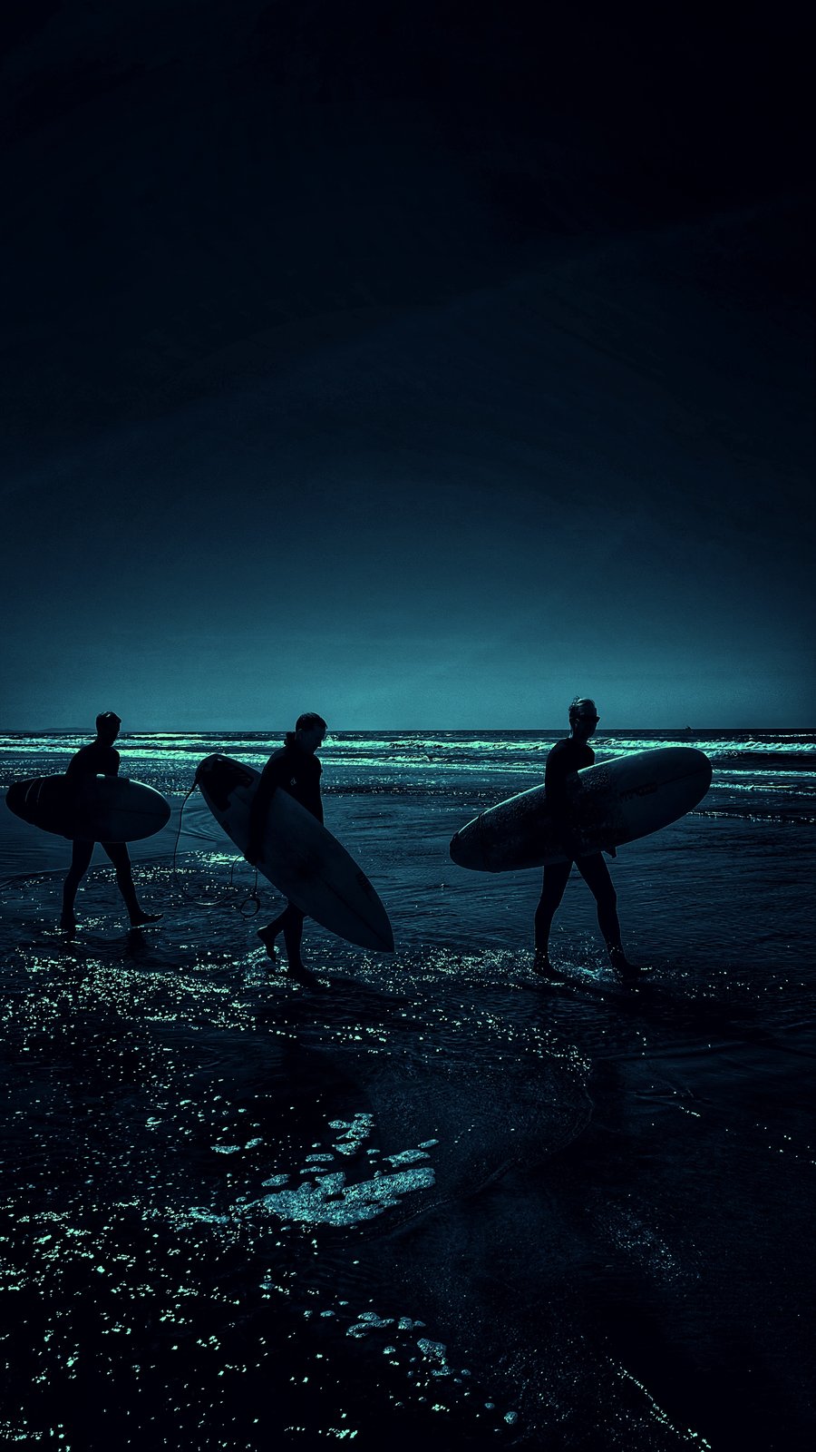 Three surfers at dusk