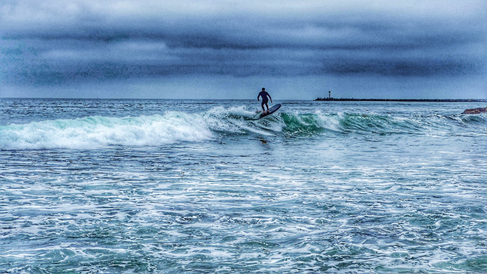 Lone surfer under a grey sky
